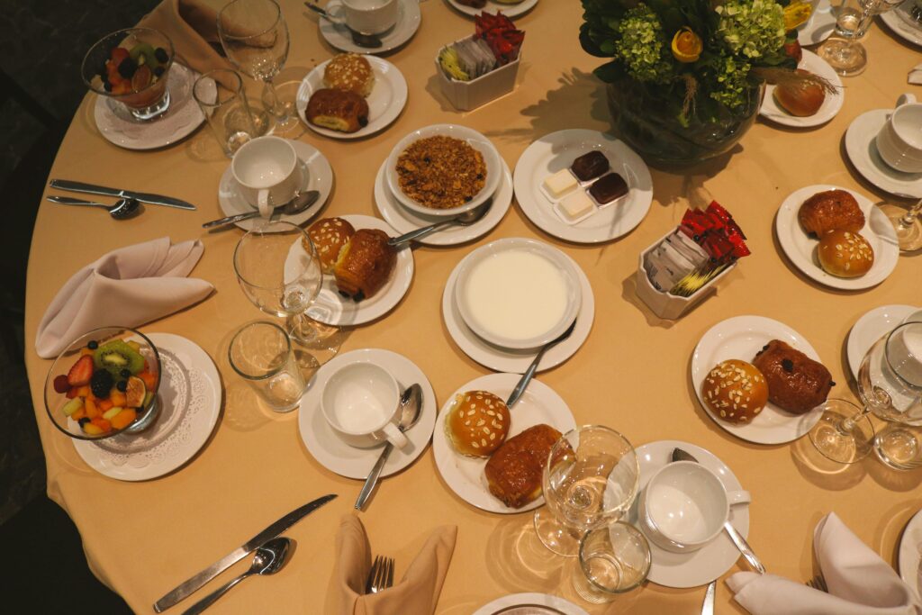 Top view of a breakfast table with pastries, fruit salad, and beverages, showcasing an elegant dining setting.